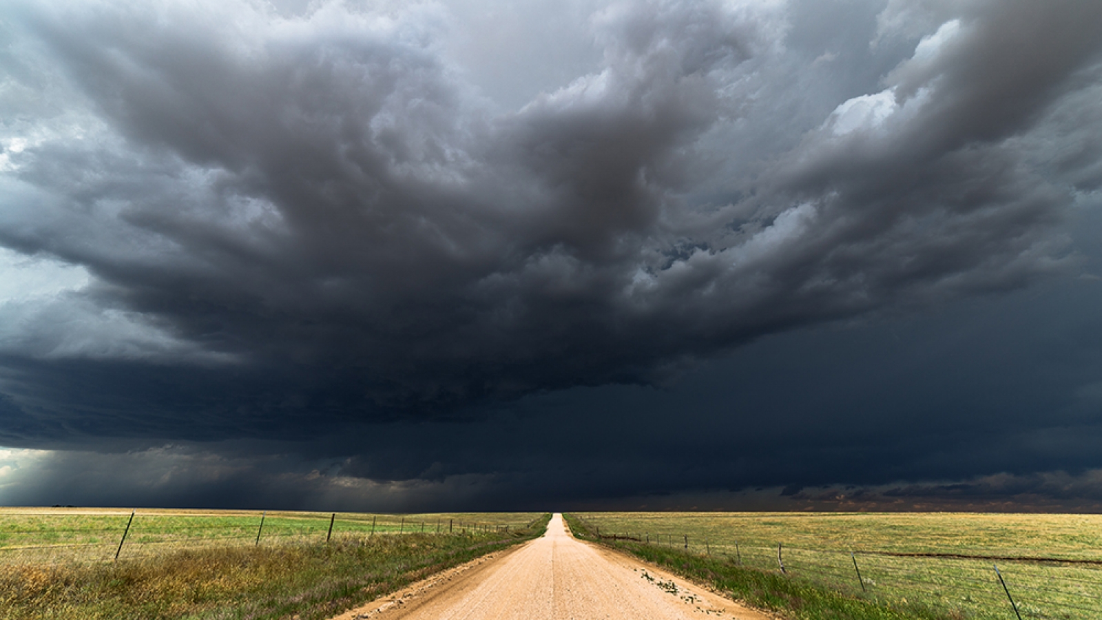 dirt road leading to storm on horizon