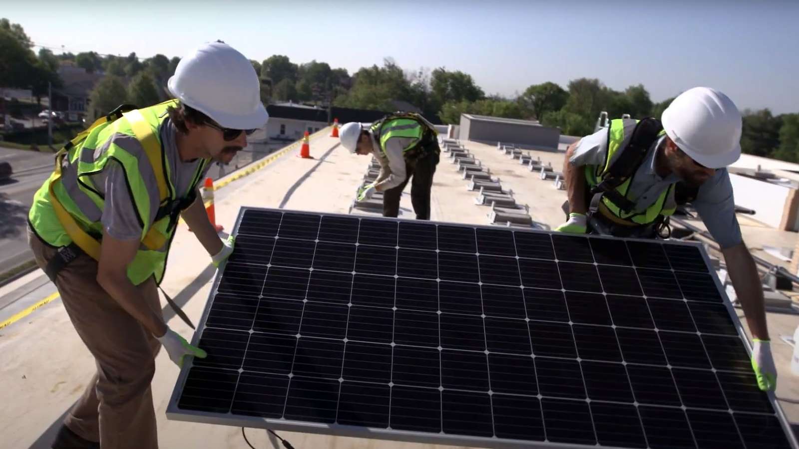 workers installing a solar panel on a roof