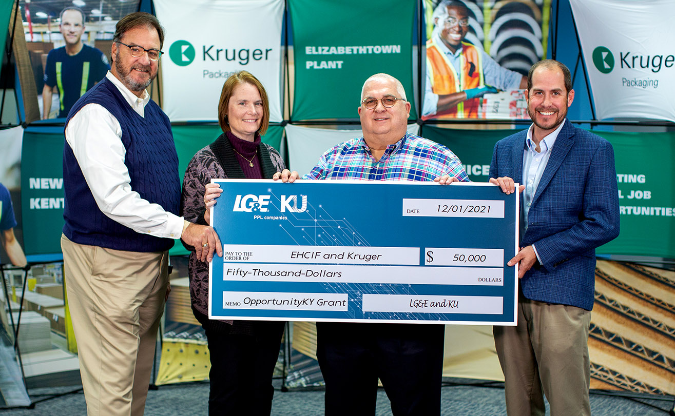 four people holding a giant check