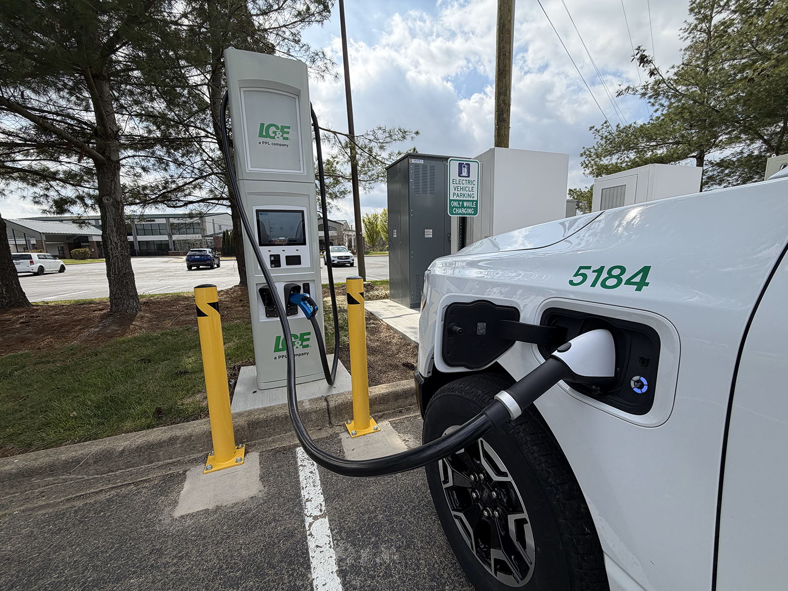 A white EV SUV parked next to an EV charger while connected