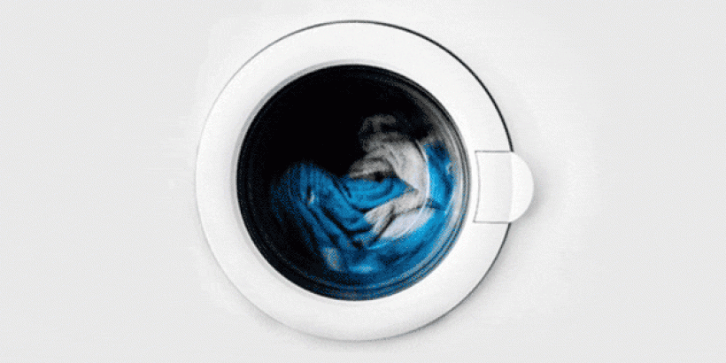 front of a washer with clothes turning inside of it