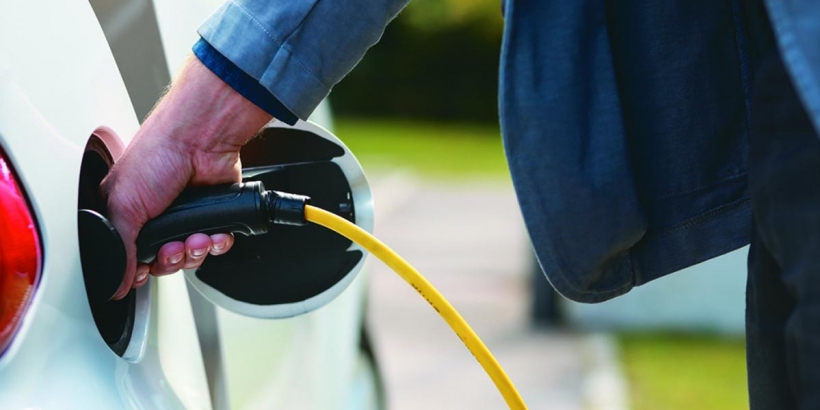 man inserting charger into electric vehicle