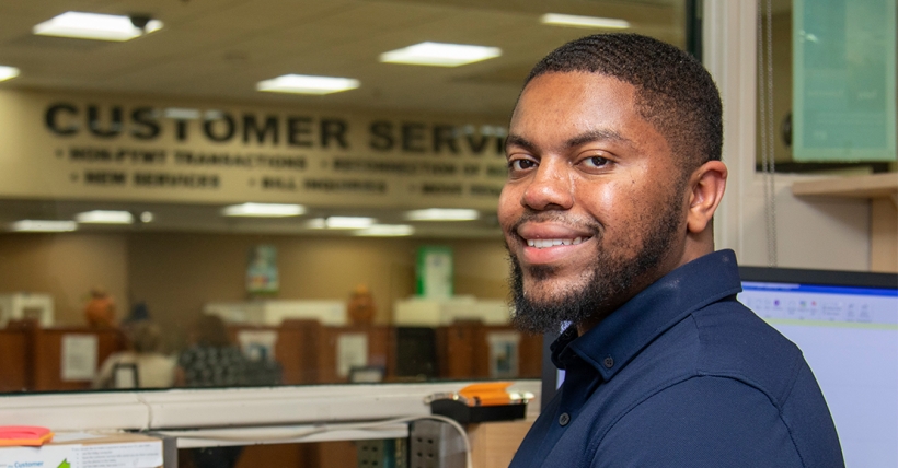 Man looking at camera from behind a customer service desk