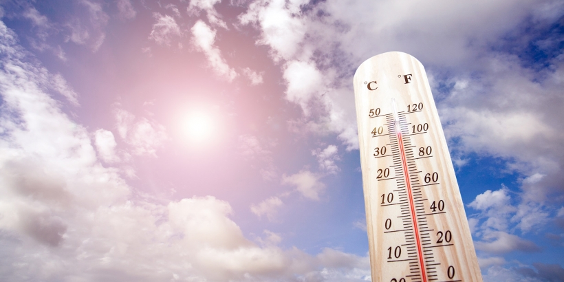 a thermometer with a sun and clouds background