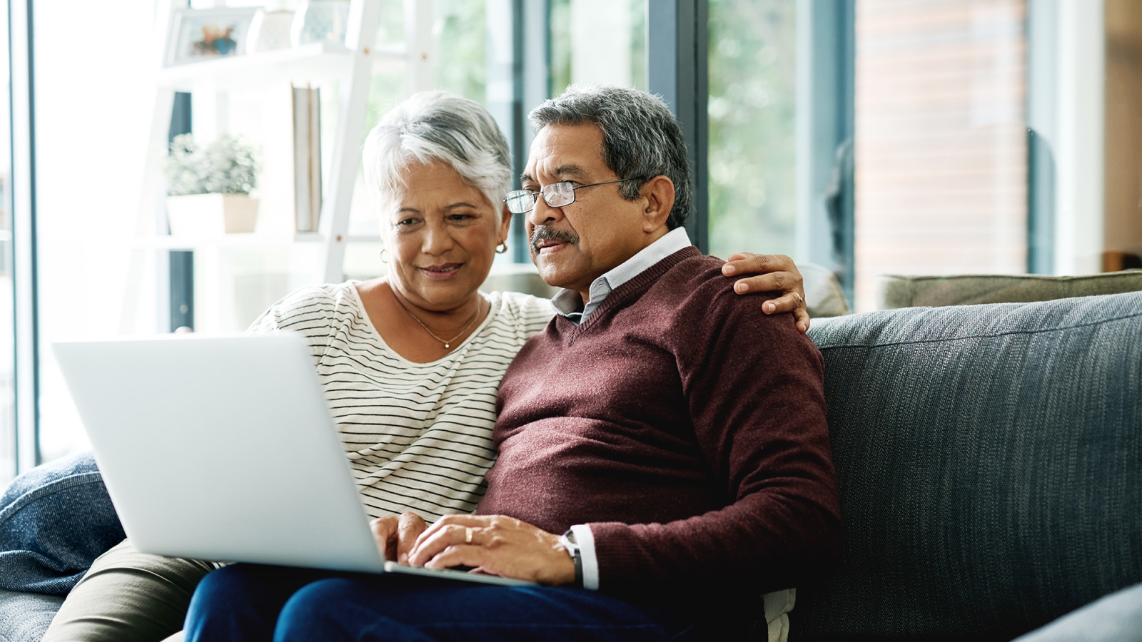 couple sitting on couch looking at laptop