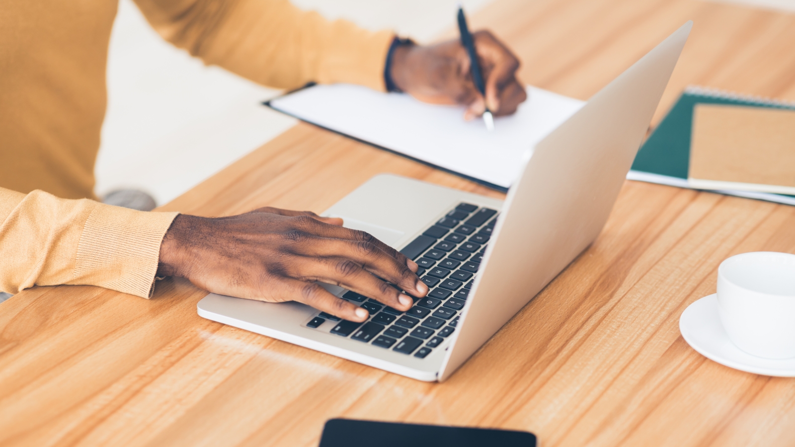 view of a table with a man on a laptop and checking things off a list