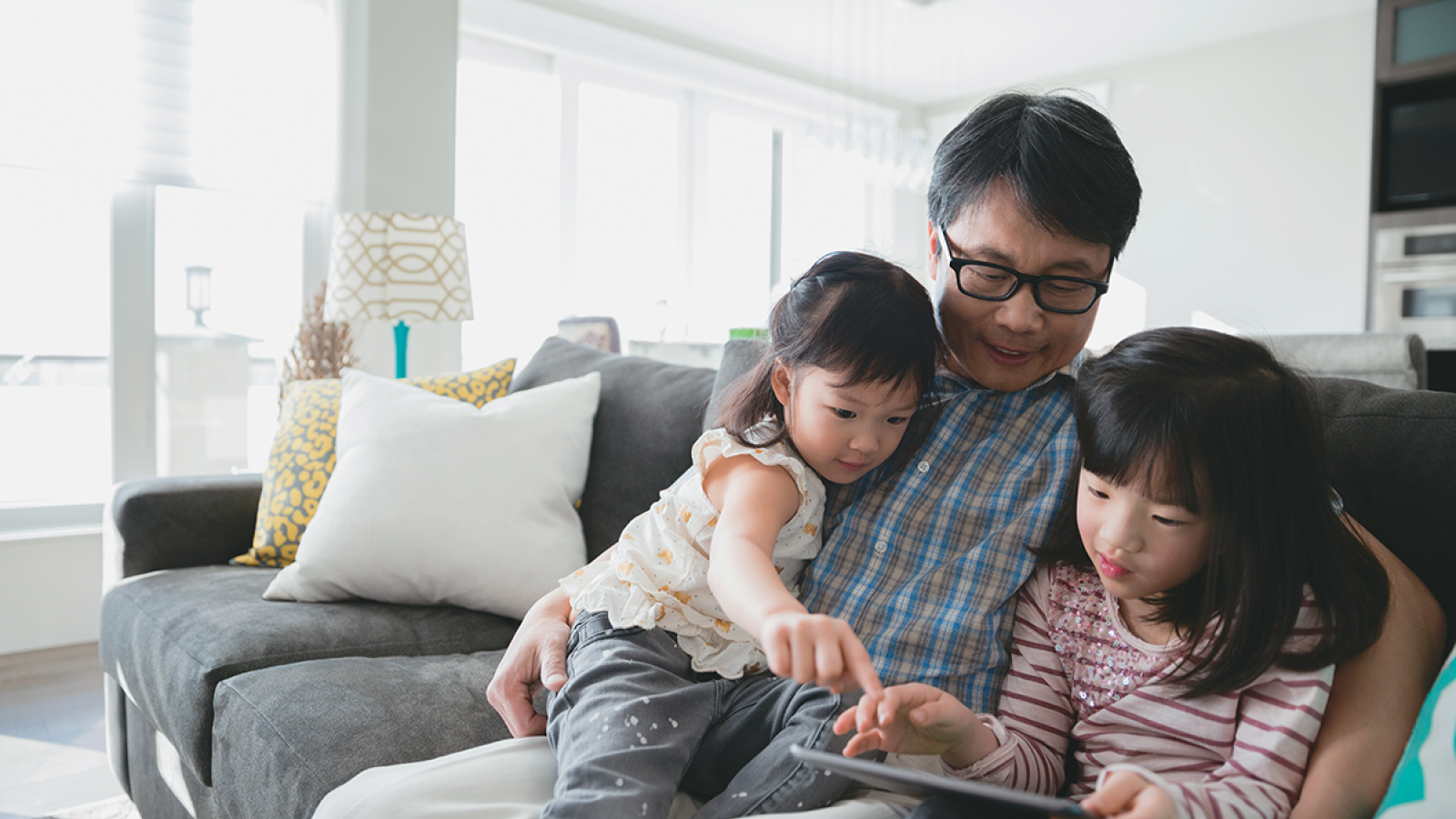 father sitting on a couch with his two daughters