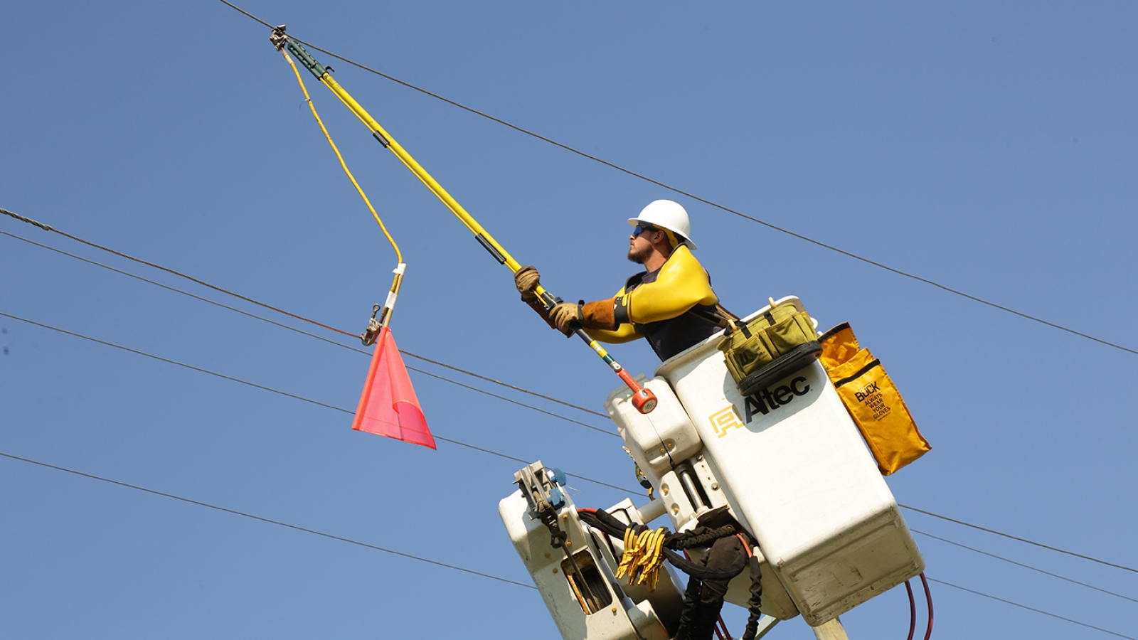 line technician in a bucket working safely on power lines