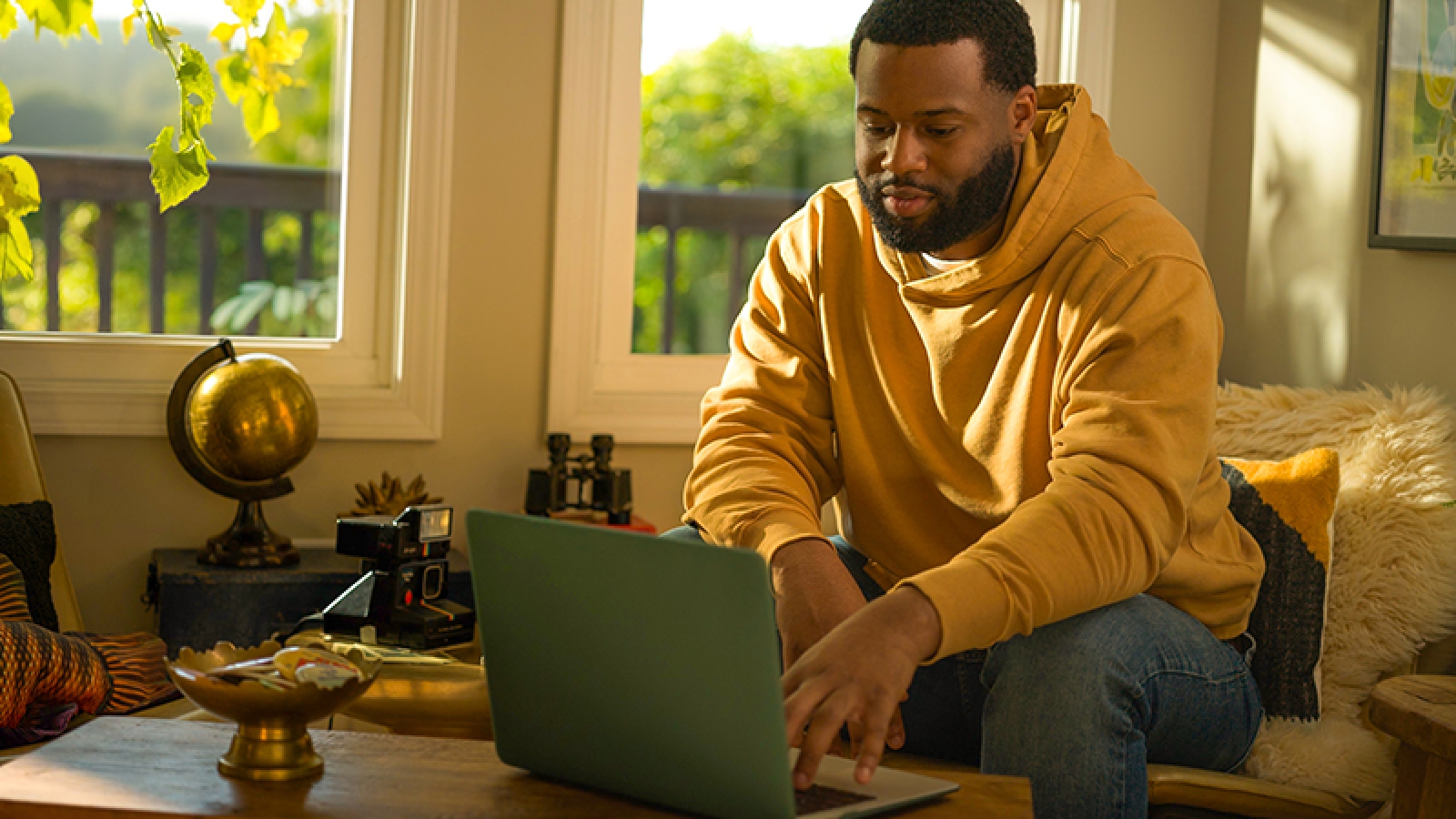 person sitting on a chair in a living room, working on a laptop on a coffee table.