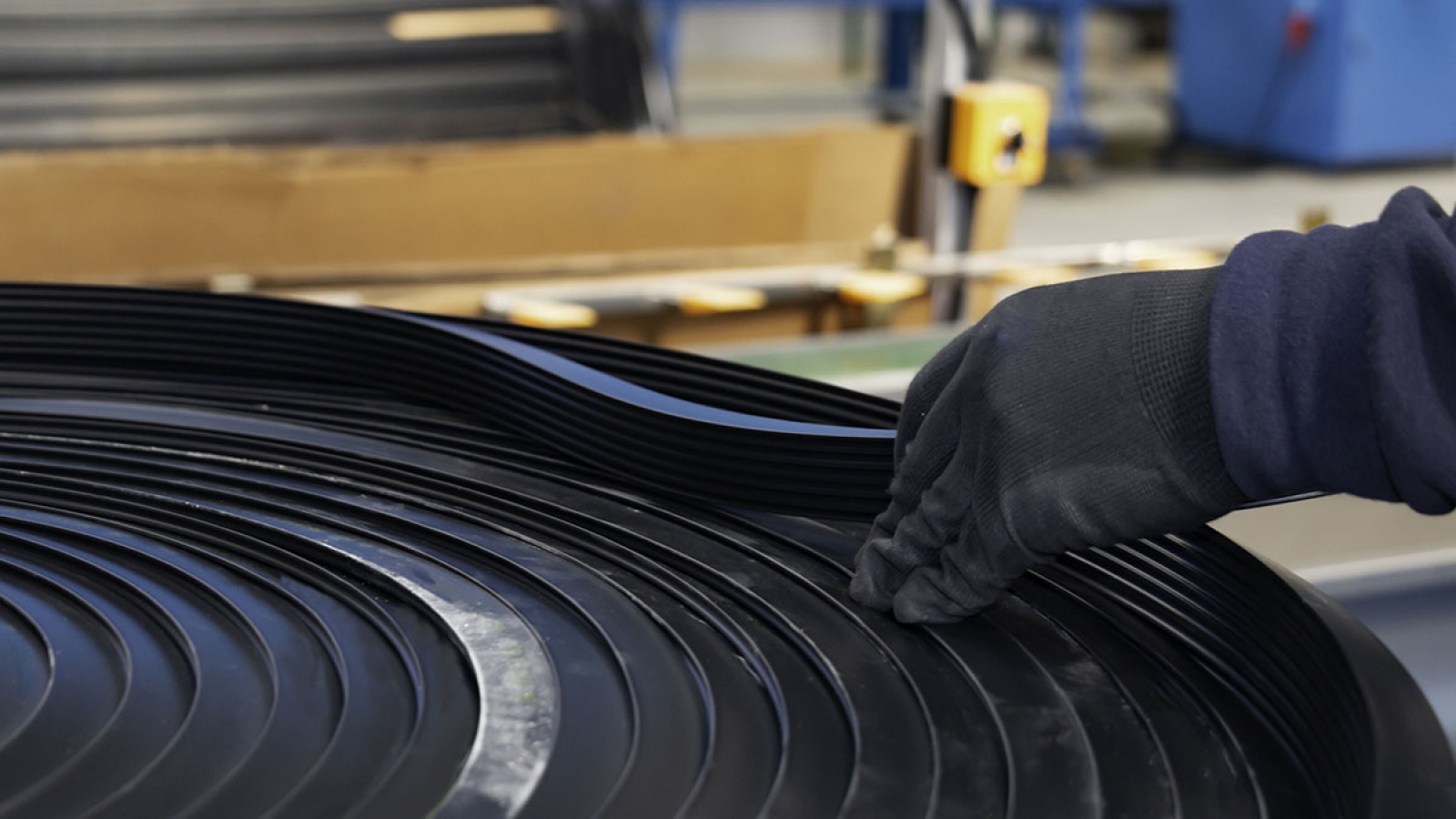 a gloved hand inspecting a coil of rubber