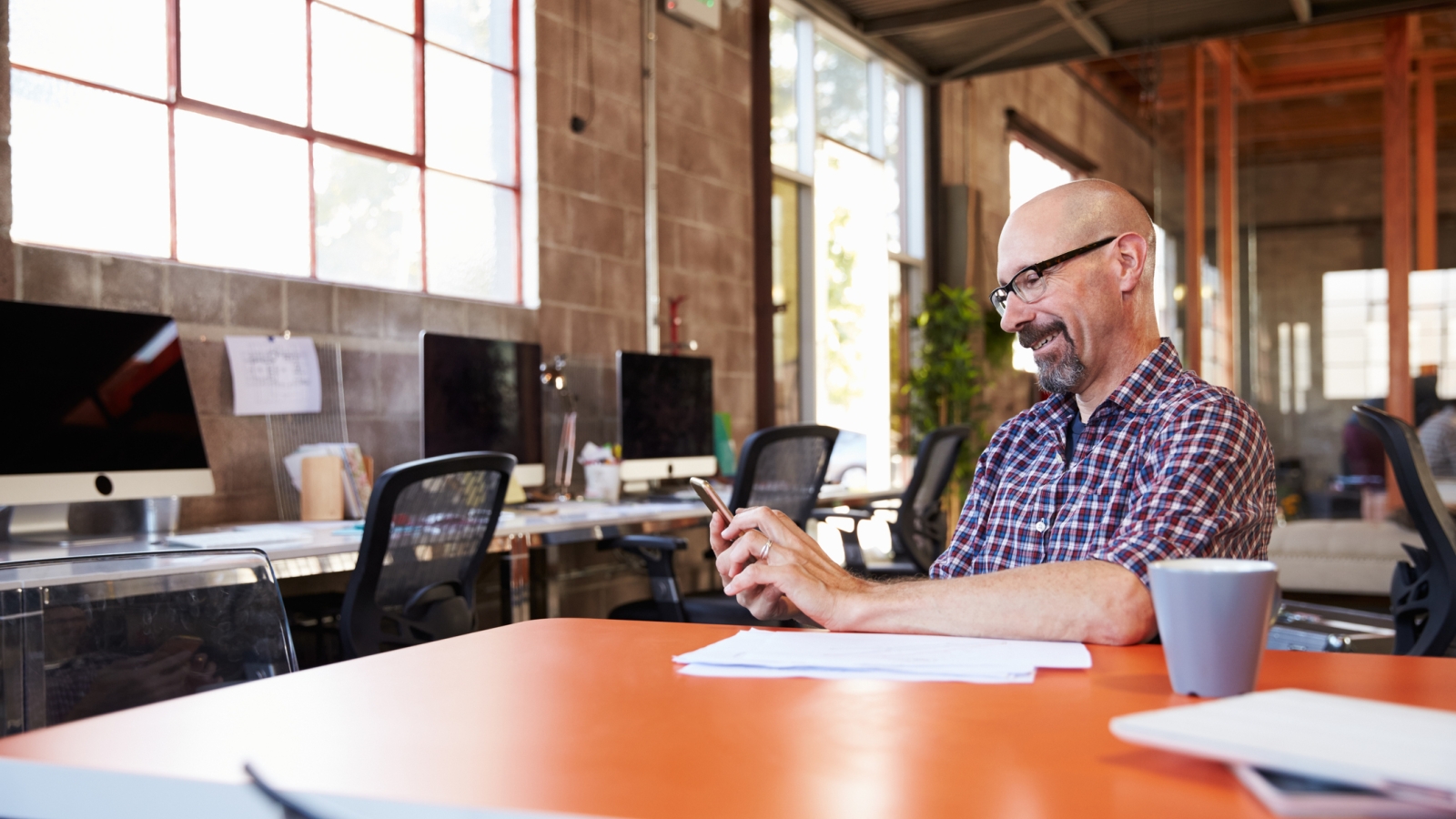 Business owner looking at mobile device at his business location.
