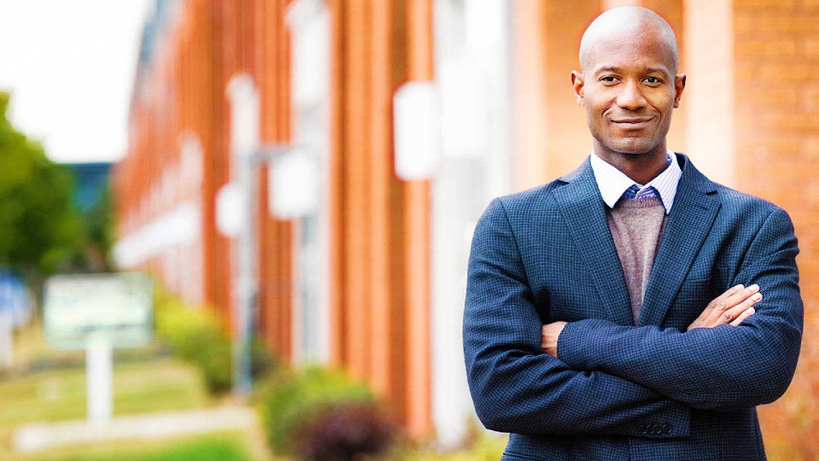 man with arms folded in front of apartments