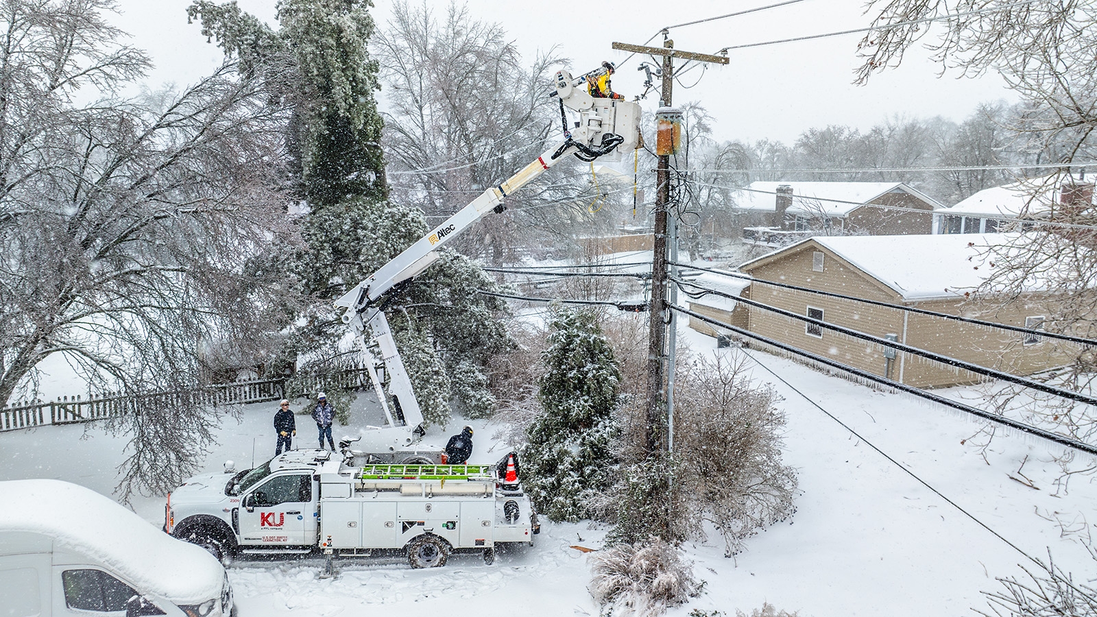 KU bucket truck extended in snow and ice restoring power line at a pole