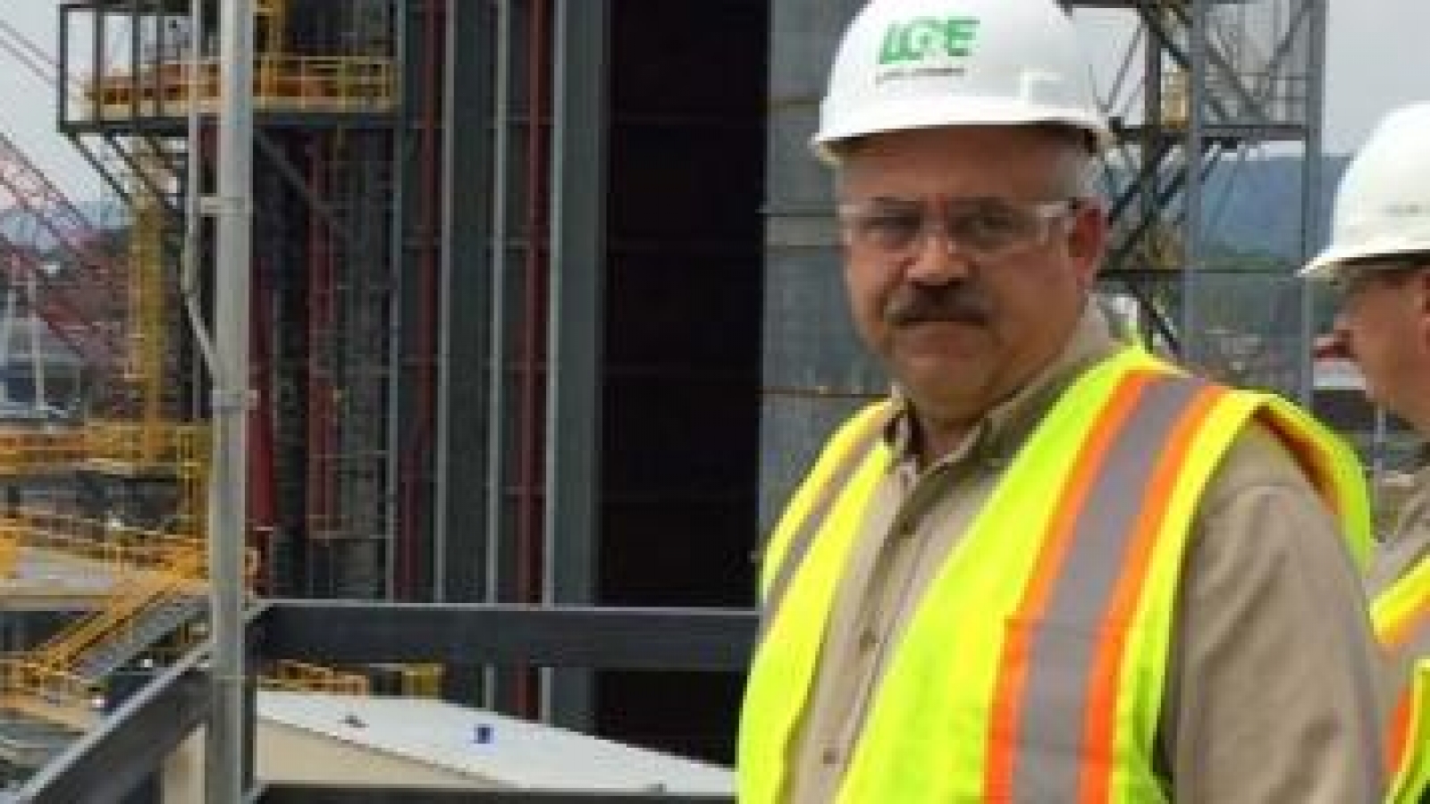 two men in hard hats and safety vests at a power plant