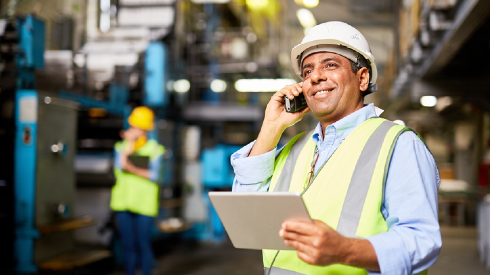 Employee with hard hat on cell phone in commercial building