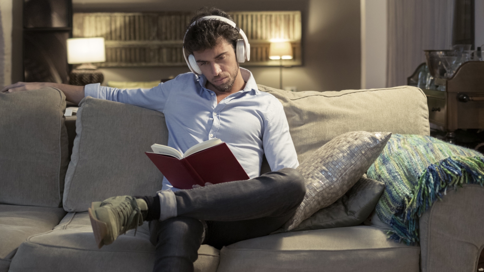 person sitting on a couch reading a book wearing headphones