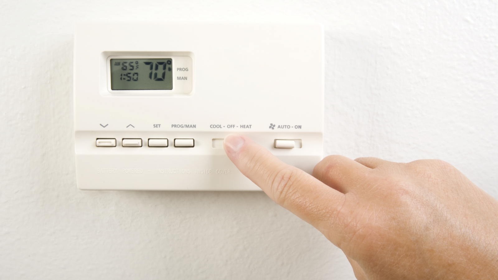 Person adjusting the thermostat