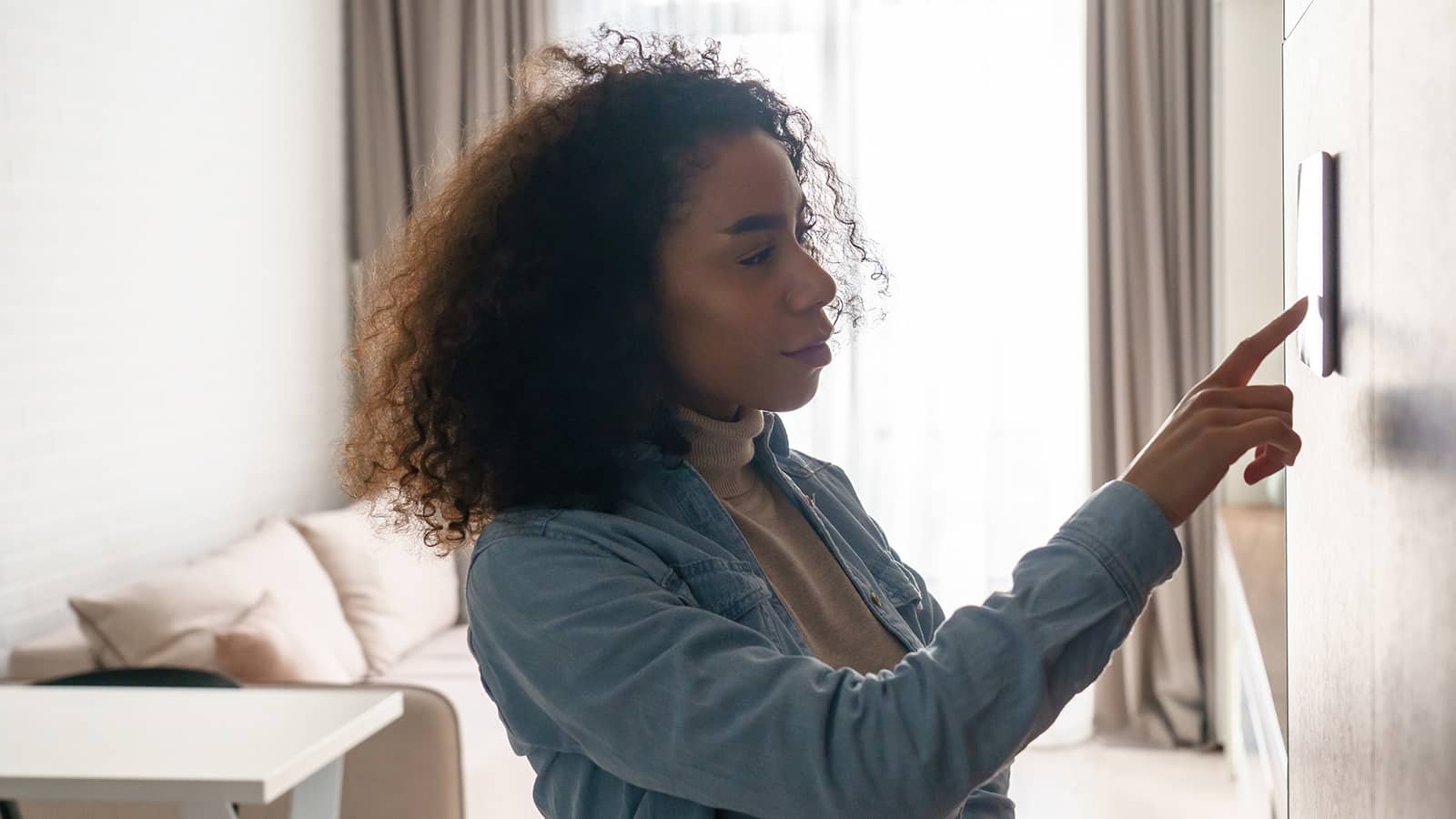 person adjusting thermostat on a wall
