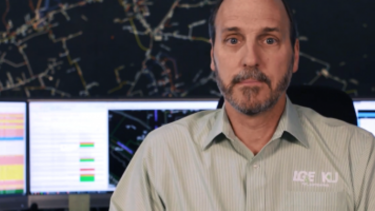 male employee in room with monitors behind him describes process
