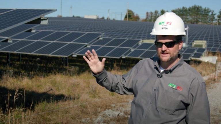 employee wearing hard hat in front of solar arrays