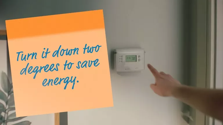 thermostat with post-it note turn it down two degrees to save energy