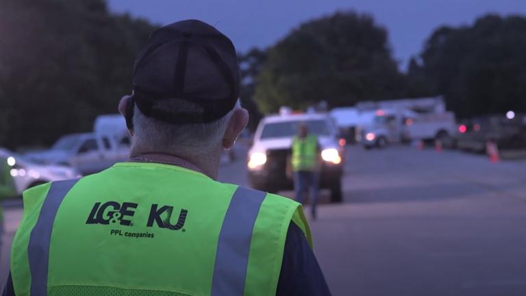 employee in safety vest looking at utility trucks
