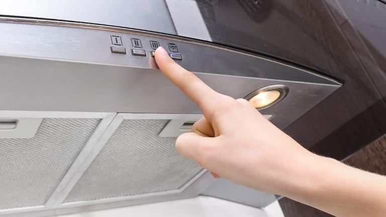 finger pressing button on an exhaust fan