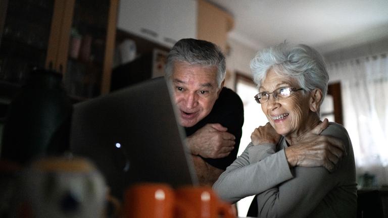 Grandparents using the hugging gesture while looking at a computer