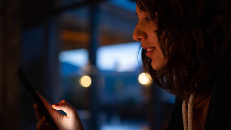 person in a darkened room on a mobile phone