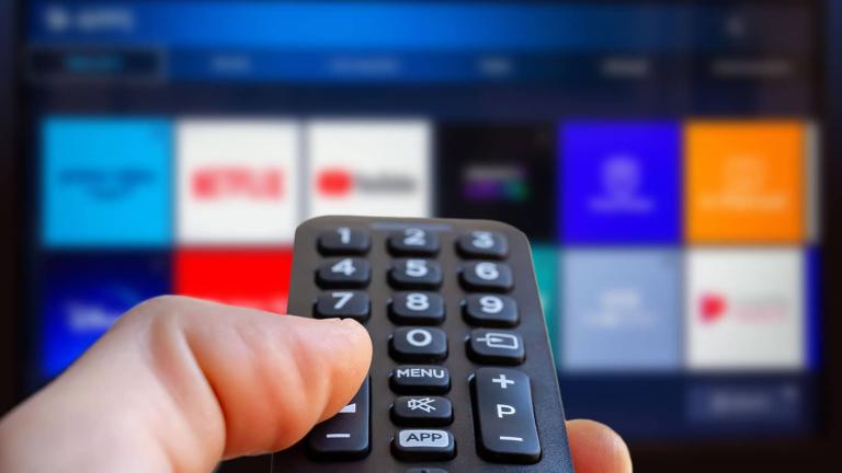 hand holding a remote control pointed at a television
