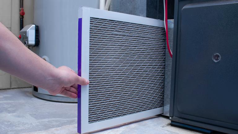 hand removing a filter from a furnace