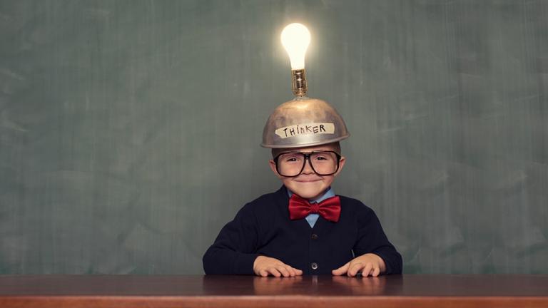 boy at table with thinker hat and light bulb