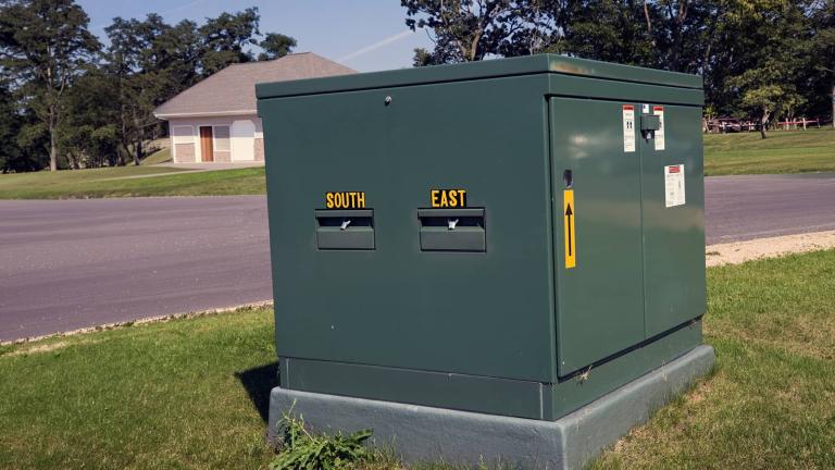 a green pad transformer in a yard next to a neighborhood street