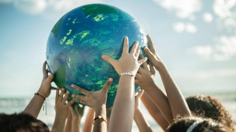 Childrens' hands holding up a globe