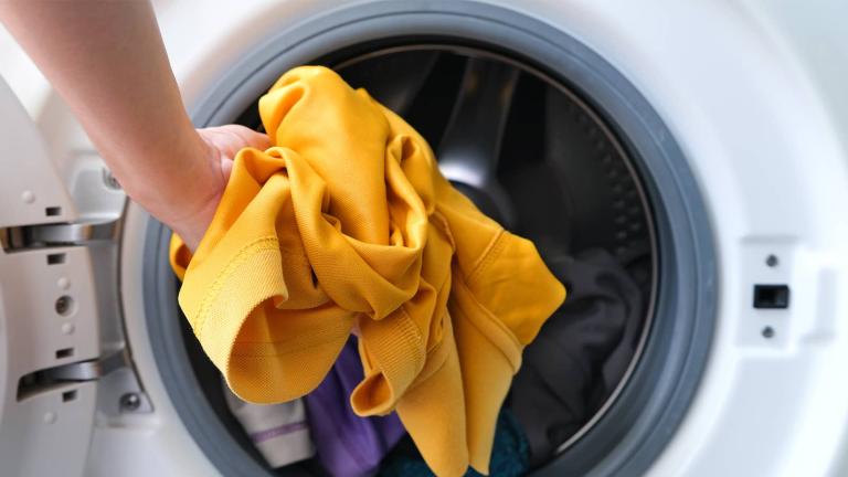 person putting clothes in dryer