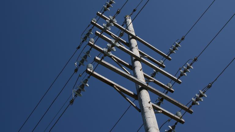 a power pole and power lines shot from the ground looking up.