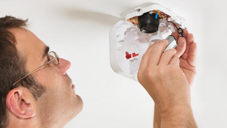 person changing battery on a smoke detector