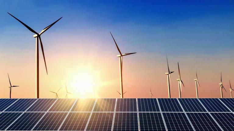 a solar array with wind turbines in the background