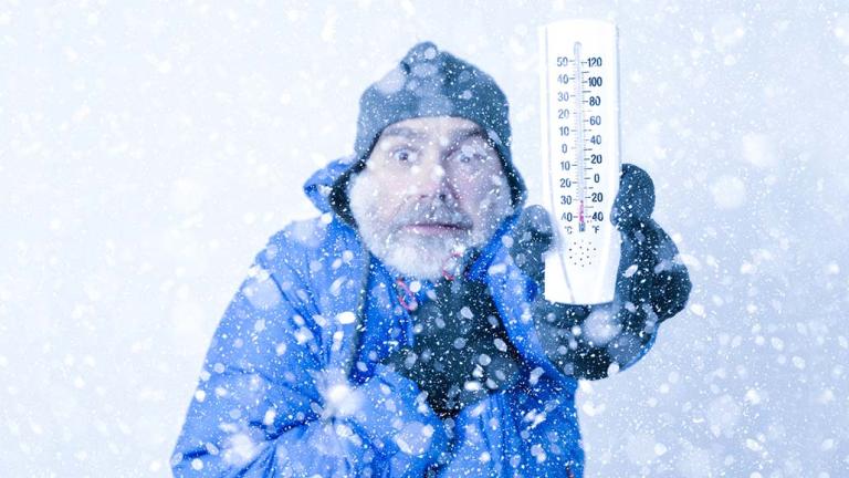 cold person in snow holding a thermometer