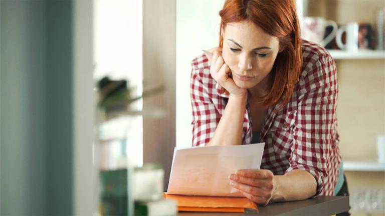 person leaning on counter reading a bill