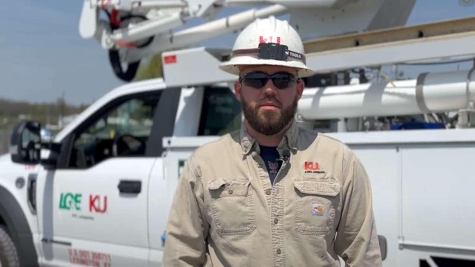 service technician wearing a hard hat standing in front of a bucket truck