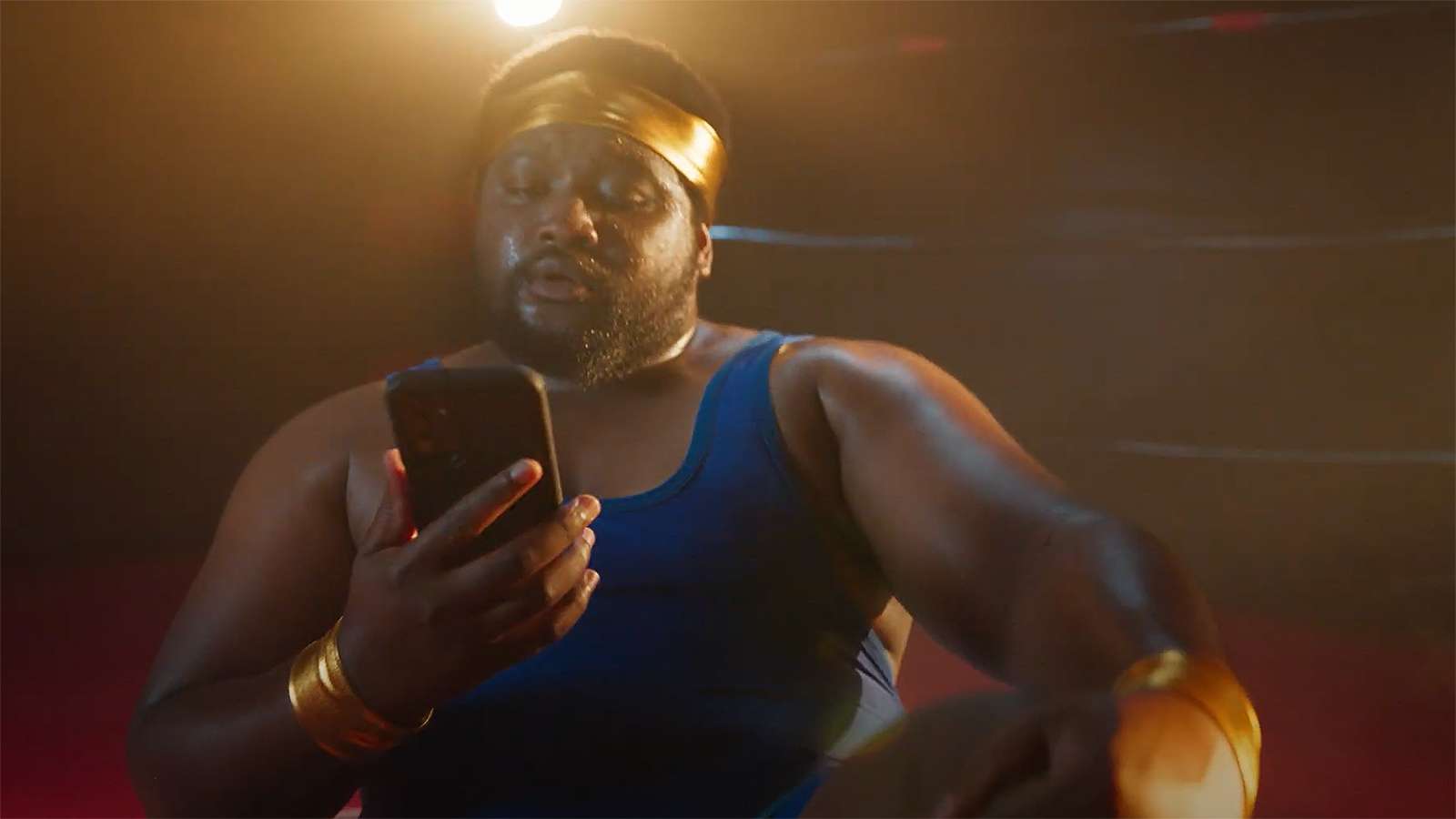 a wrestler in a ring looking at his smartphone