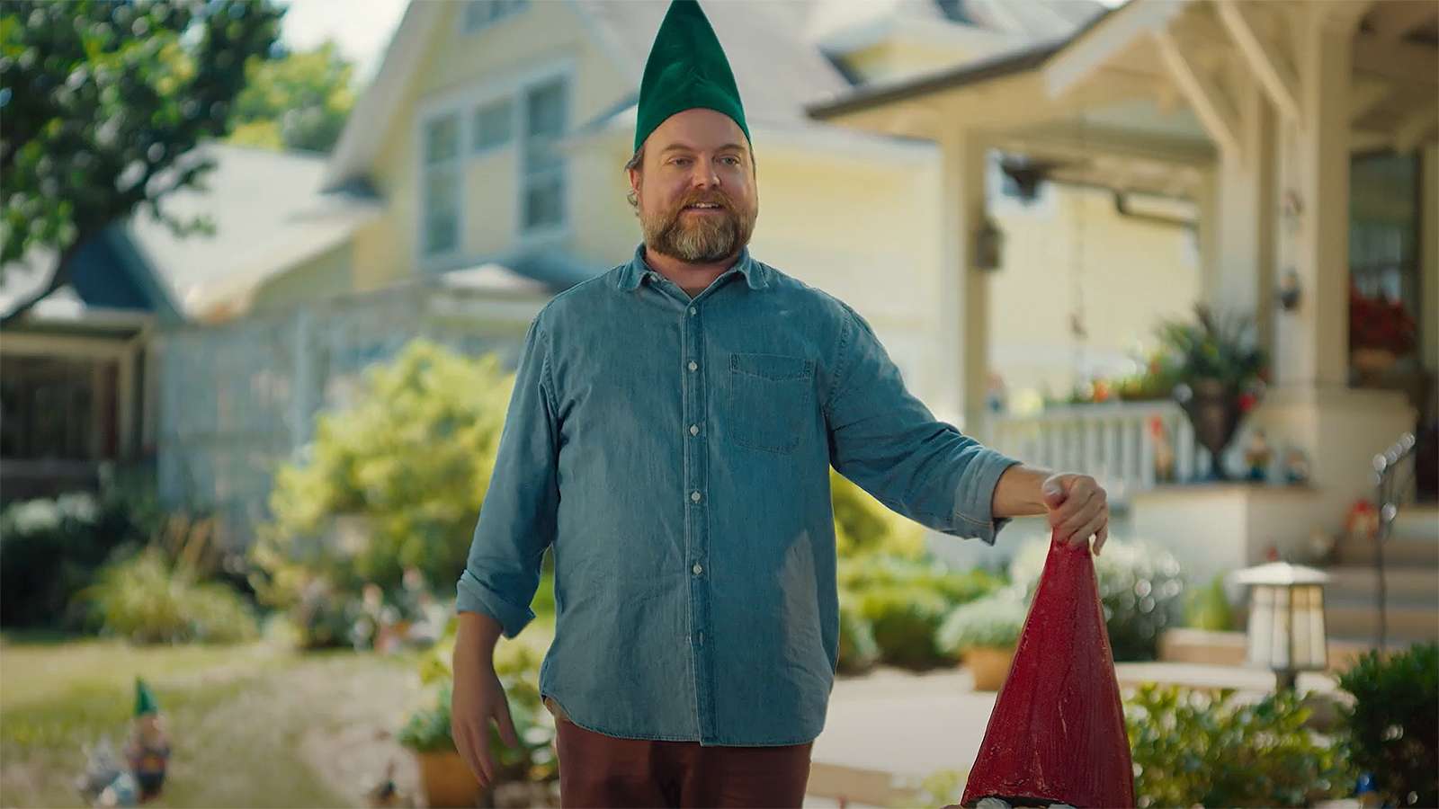 person wearing a gnome hat standing in a front yard