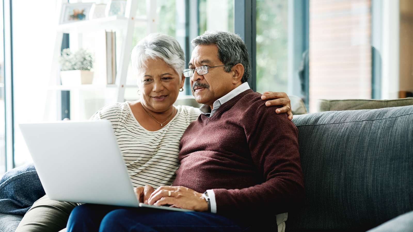couple sitting on couch looking at laptop