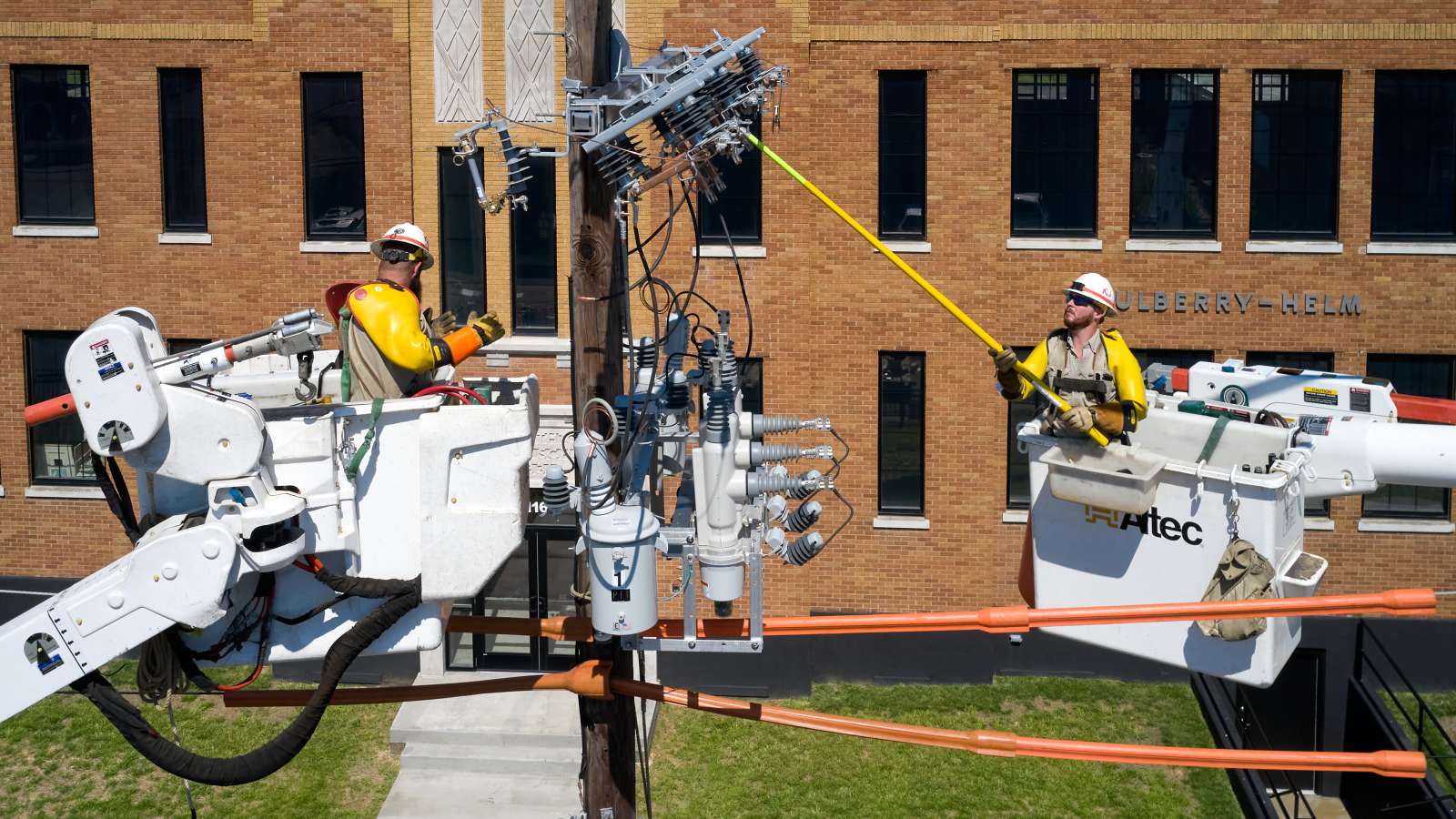 line technicians working on reclosers in buckets on a distribution power pole