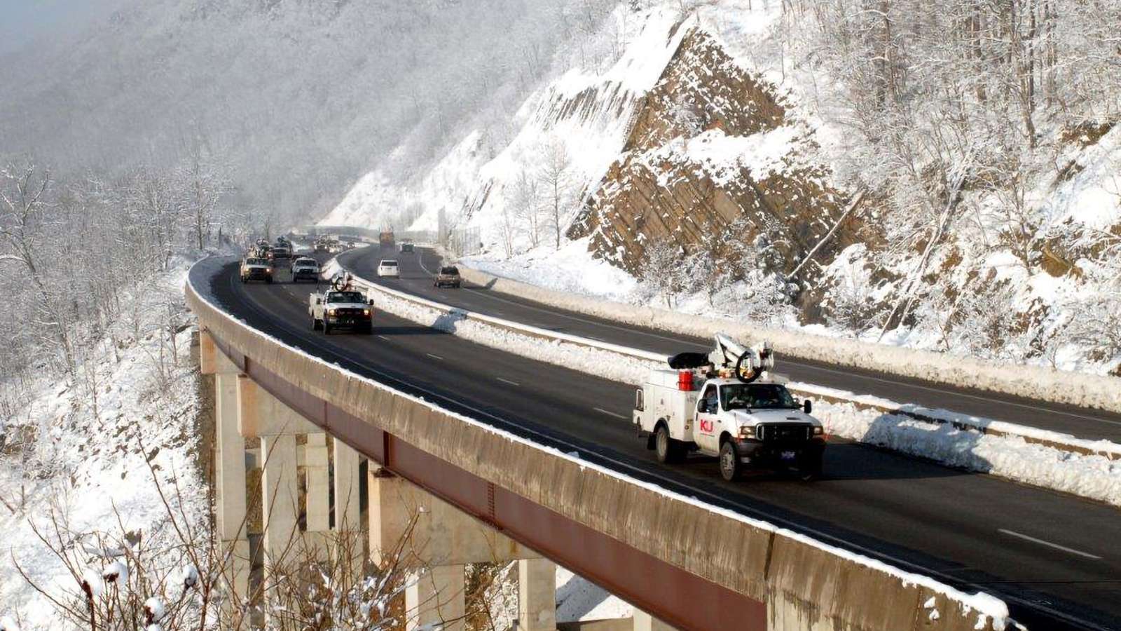 bucket trucks on a highway with a snowy mountain background