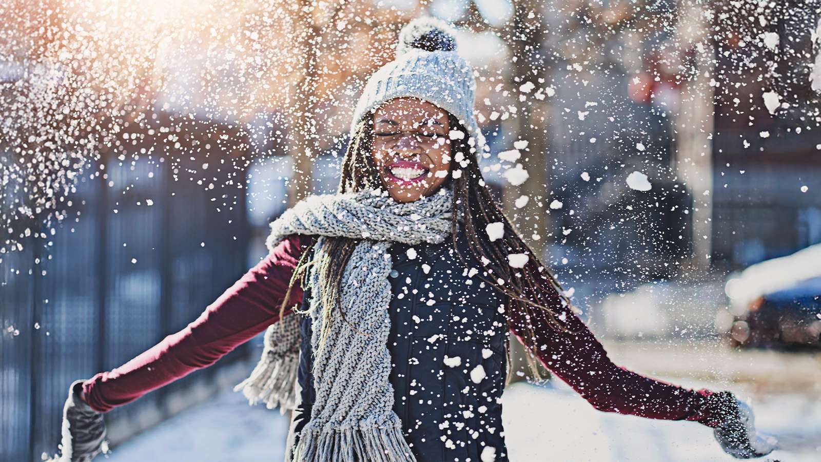 person with knit cap and scarf playing in the snow