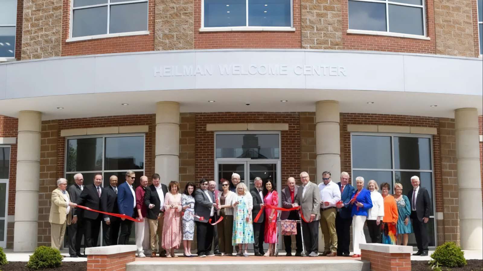 people cutting ribbon in front of new building