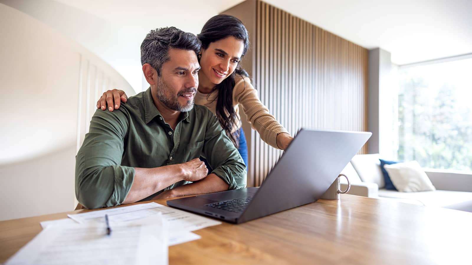 A couple in a room looking at a laptop on a desk
