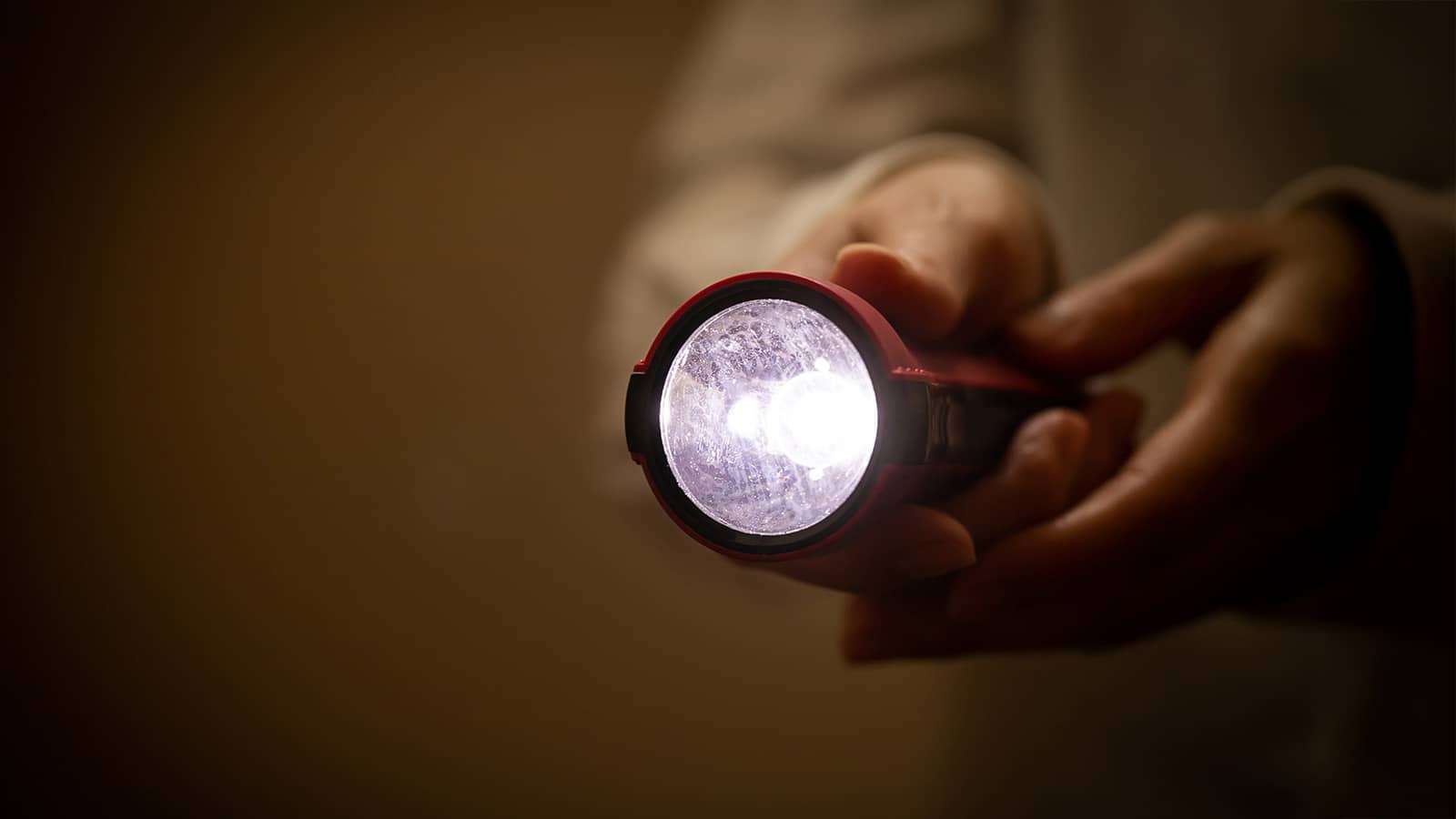 person holding a flashlight in the dark